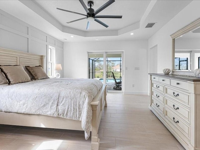 bedroom with access to exterior, a tray ceiling, and ceiling fan