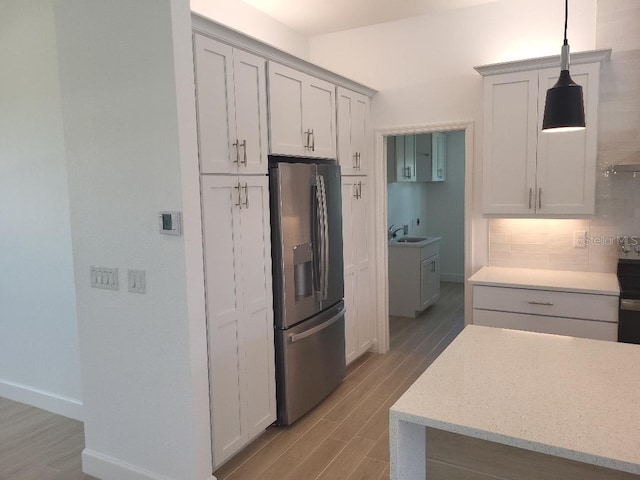 261 Broadmoor Ln, Rotonda West, FL 33947 - kitchen with stainless steel refrigerator with ice dispenser, light wood finished floors, decorative backsplash, and hanging light fixtures