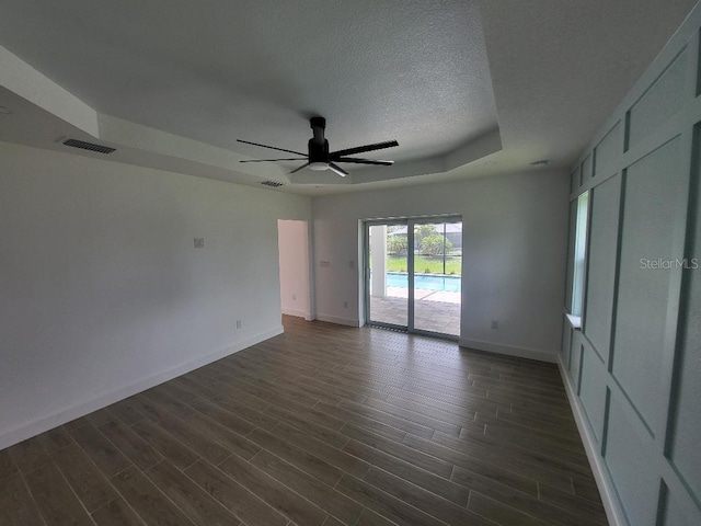 261 Broadmoor Ln, Rotonda West, FL 33947 - unfurnished bedroom with access to exterior, dark wood finished floors, a textured ceiling, a raised ceiling, and a ceiling fan