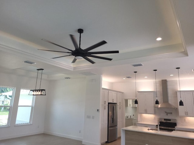 261 Broadmoor Ln, Rotonda West, FL 33947 - kitchen featuring wall chimney range hood, a raised ceiling, stainless steel appliances, crown molding, and light countertops