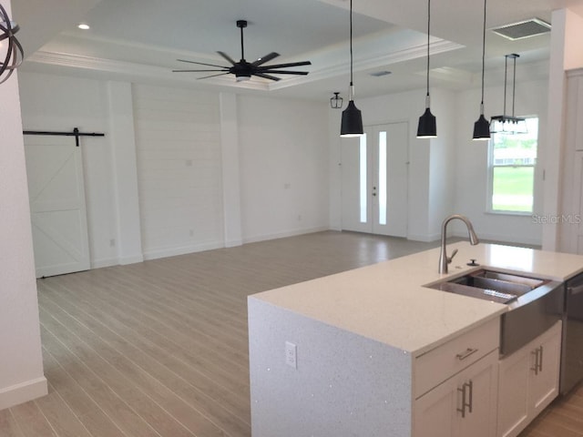 261 Broadmoor Ln, Rotonda West, FL 33947 - kitchen with a tray ceiling, a barn door, light wood-type flooring, hanging light fixtures, and a ceiling fan