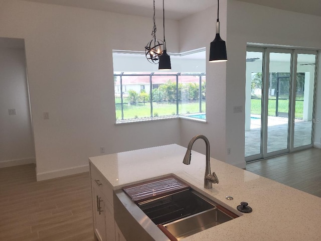 261 Broadmoor Ln, Rotonda West, FL 33947 - kitchen featuring wood finished floors, plenty of natural light, light stone countertops, and pendant lighting
