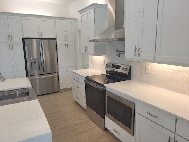 261 Broadmoor Ln, Rotonda West, FL 33947 - kitchen with appliances with stainless steel finishes, wall chimney exhaust hood, tasteful backsplash, light wood-style flooring, and light stone countertops