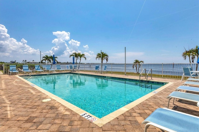 view of pool with a patio area and a water view