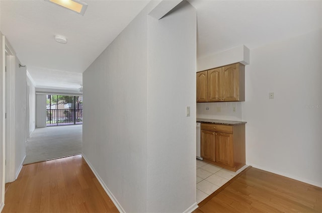 corridor featuring light wood-style floors and baseboards