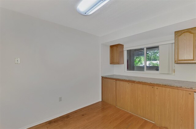 kitchen with light hardwood / wood-style flooring, light brown cabinetry, and light stone countertops