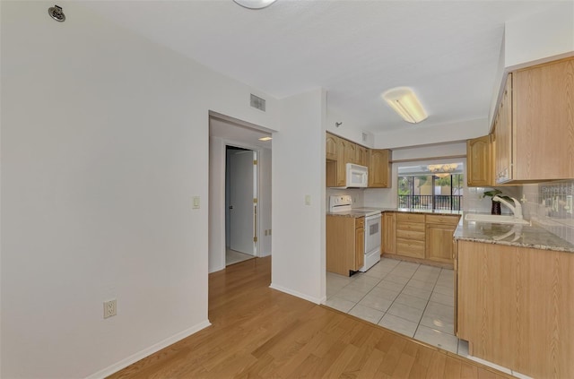 kitchen with visible vents, light brown cabinetry, light wood-style floors, a sink, and white appliances