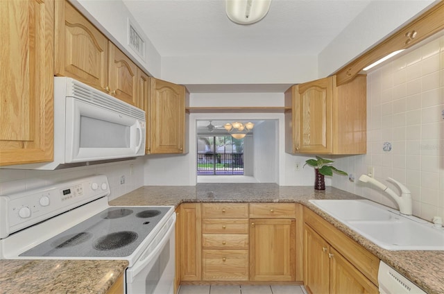 kitchen featuring light tile patterned floors, white appliances, a sink, visible vents, and decorative backsplash