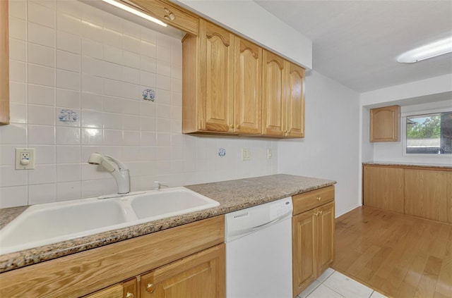 kitchen with light tile patterned floors, decorative backsplash, white dishwasher, light countertops, and a sink