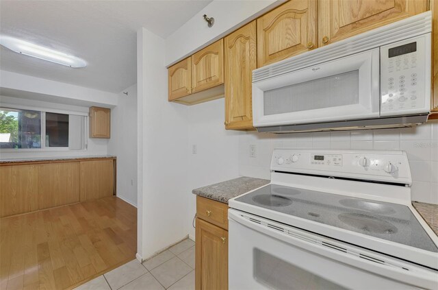 kitchen featuring light brown cabinetry, light hardwood / wood-style flooring, and white appliances