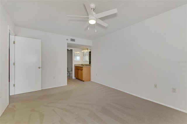 unfurnished bedroom featuring ensuite bath, light carpet, and ceiling fan