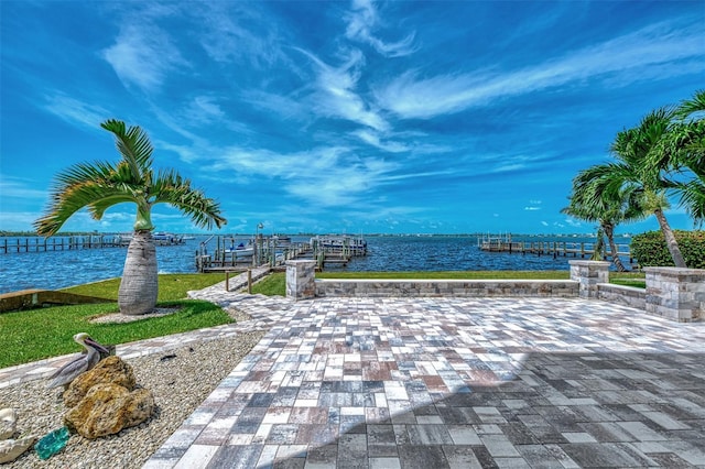 view of property's community featuring a patio, a water view, and a dock