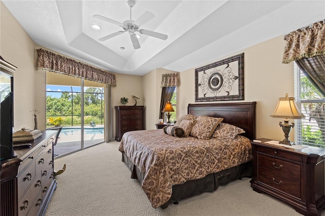 carpeted bedroom featuring access to outside, a raised ceiling, ceiling fan, and a textured ceiling