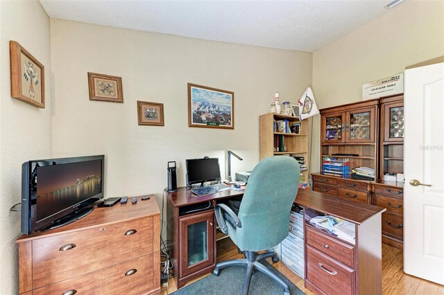 home office with light wood-type flooring and vaulted ceiling