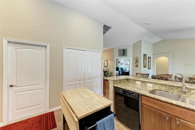 kitchen with lofted ceiling, dishwasher, light stone countertops, light tile patterned floors, and sink