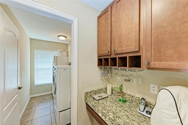 washroom with cabinets, light tile patterned floors, and washer and dryer