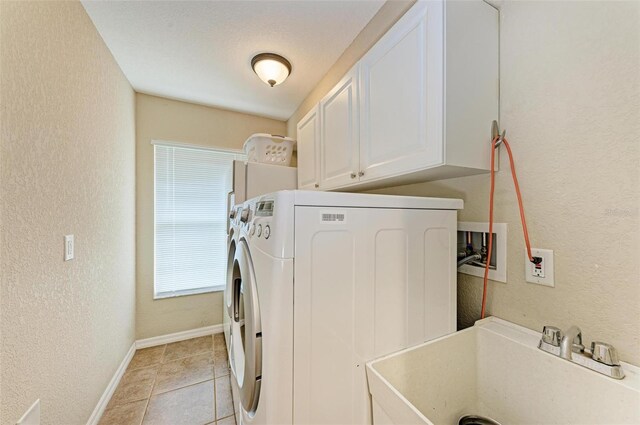 laundry room with washing machine and dryer, sink, light tile patterned floors, and cabinets