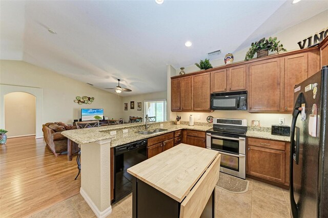 kitchen featuring light hardwood / wood-style flooring, a breakfast bar area, lofted ceiling, black appliances, and sink