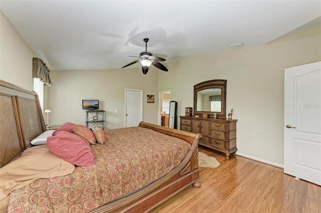 bedroom featuring hardwood / wood-style floors, lofted ceiling, a textured ceiling, and ceiling fan