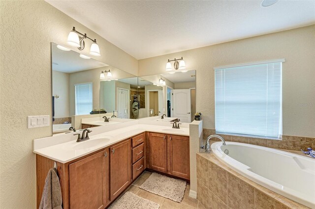 bathroom with double vanity, a textured ceiling, tiled tub, and tile patterned flooring