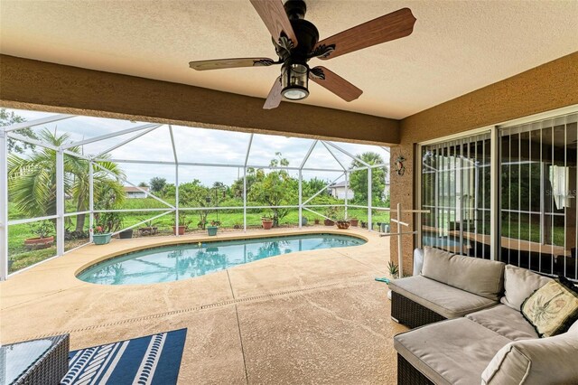 view of swimming pool with ceiling fan, a patio, outdoor lounge area, and a lanai