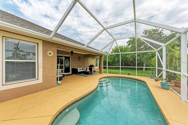 view of swimming pool featuring ceiling fan, glass enclosure, and a patio area