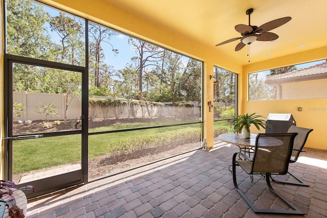 sunroom with a water view and ceiling fan