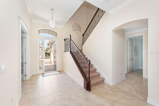 entrance foyer with light tile patterned floors, baseboards, arched walkways, and crown molding