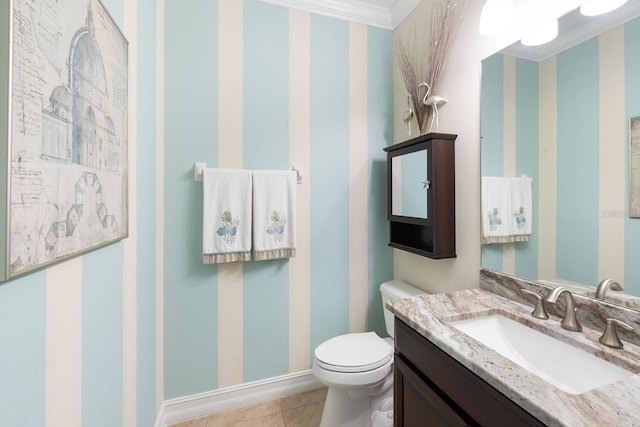 bathroom with toilet, vanity, tile patterned flooring, baseboards, and wallpapered walls