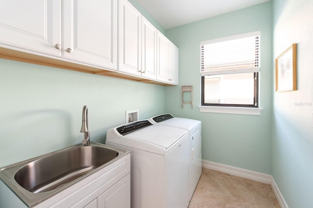 washroom with light tile patterned floors, a sink, baseboards, independent washer and dryer, and cabinet space