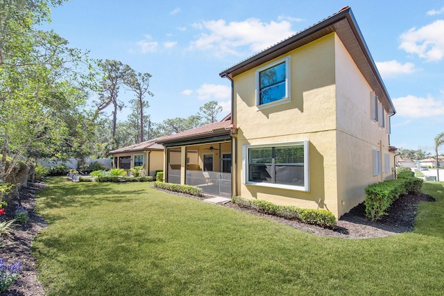 back of house with a yard, a sunroom, and stucco siding