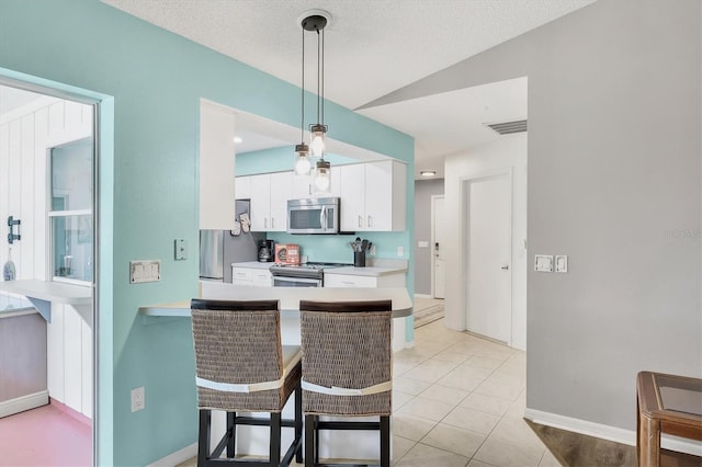 kitchen with stainless steel appliances, light countertops, hanging light fixtures, visible vents, and white cabinets