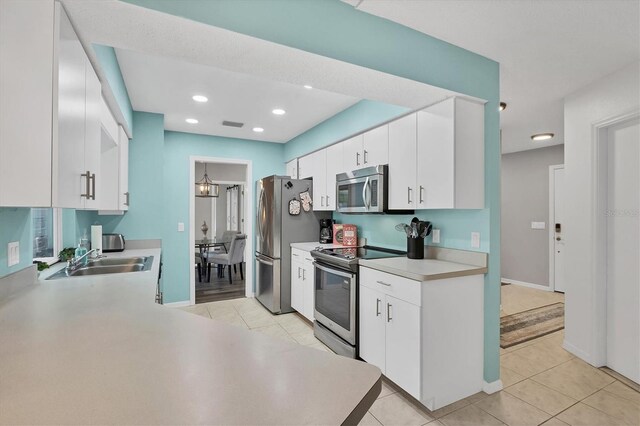 kitchen with appliances with stainless steel finishes, light tile patterned flooring, and white cabinets