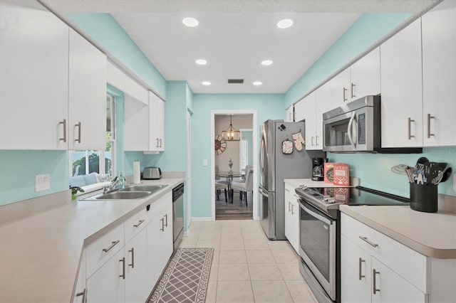 kitchen with white cabinets, a sink, stainless steel appliances, and light countertops