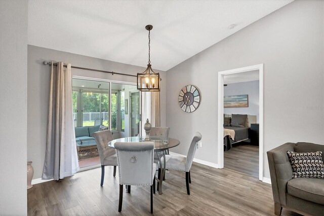 dining room featuring a notable chandelier, vaulted ceiling, and hardwood / wood-style floors