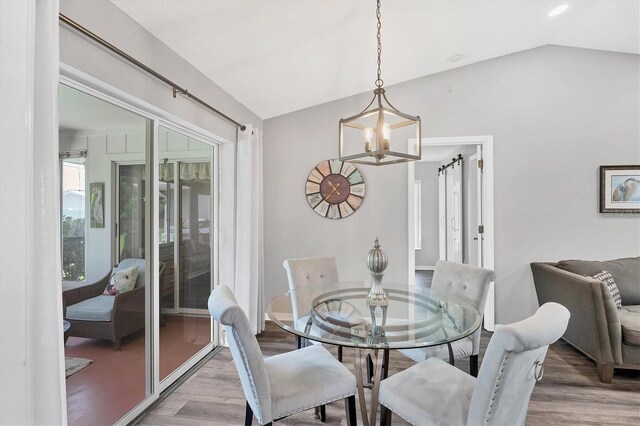 dining room featuring an inviting chandelier, lofted ceiling, and hardwood / wood-style floors