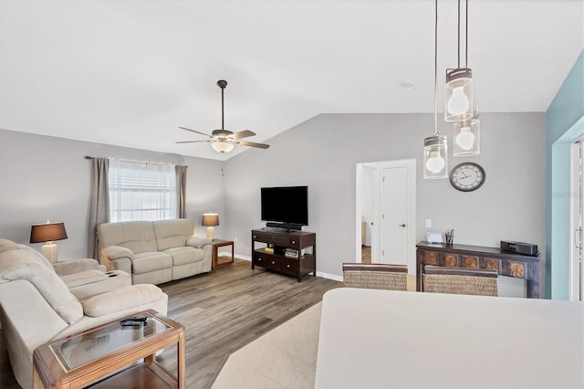 living area with lofted ceiling, ceiling fan, wood finished floors, and baseboards