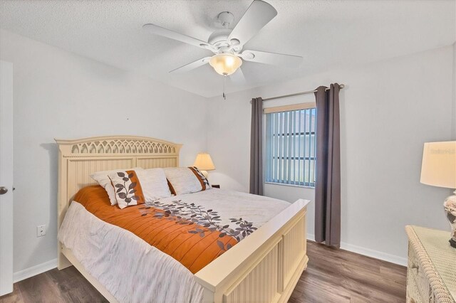 bedroom featuring a textured ceiling, dark wood-type flooring, a ceiling fan, and baseboards