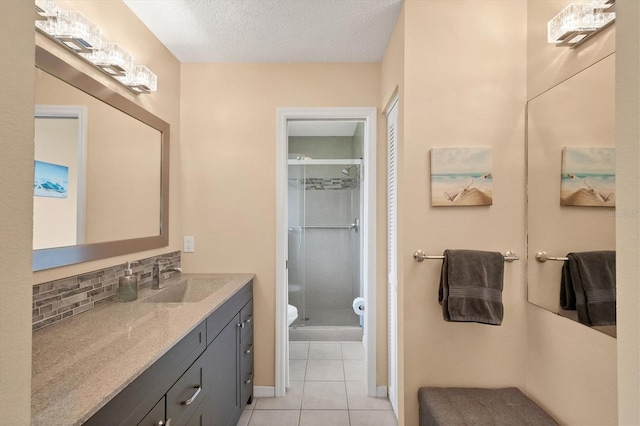 bathroom with toilet, vanity, a shower stall, tile patterned floors, and tasteful backsplash