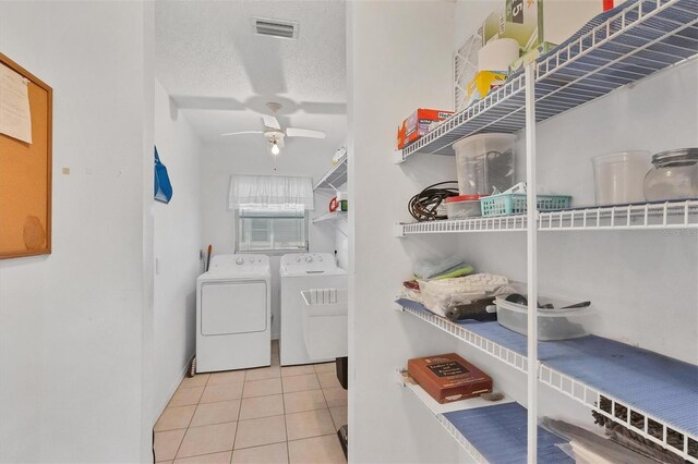 clothes washing area featuring ceiling fan, washing machine and dryer, a textured ceiling, and light tile patterned floors