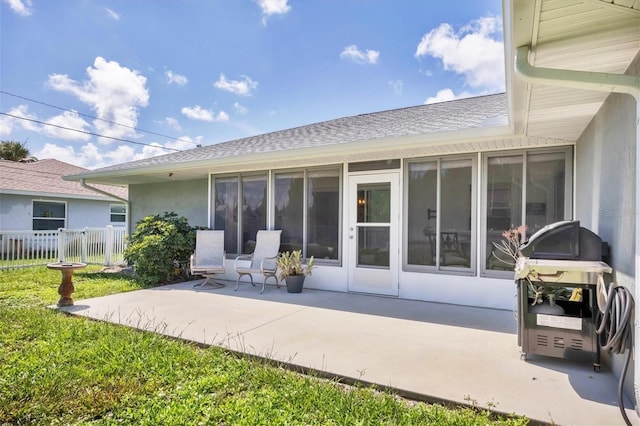 back of house featuring a patio, fence, a sunroom, roof with shingles, and stucco siding