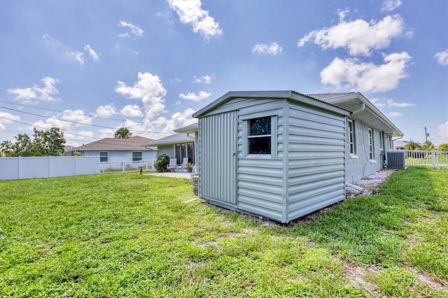 exterior space featuring a fenced backyard, cooling unit, a lawn, and an outdoor structure