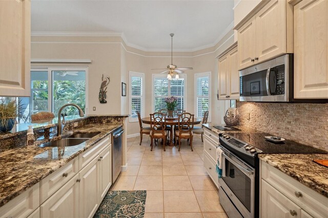 kitchen featuring sink, ornamental molding, dark stone counters, appliances with stainless steel finishes, and decorative backsplash