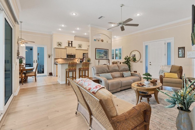 living room with ornamental molding, ceiling fan, and light hardwood / wood-style flooring