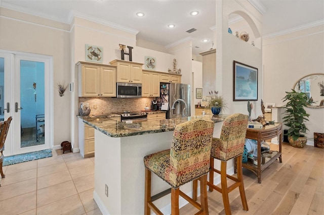 kitchen featuring appliances with stainless steel finishes, a kitchen breakfast bar, dark stone countertops, french doors, and kitchen peninsula