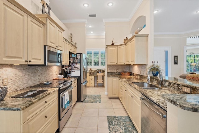 kitchen featuring appliances with stainless steel finishes, ornamental molding, light tile patterned floors, sink, and dark stone countertops