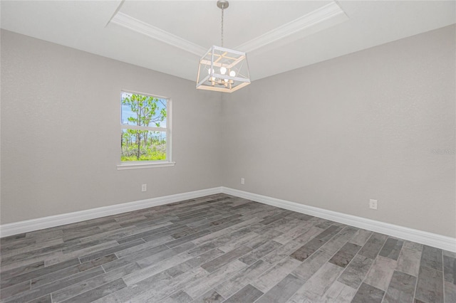 empty room featuring an inviting chandelier, wood-type flooring, and a raised ceiling