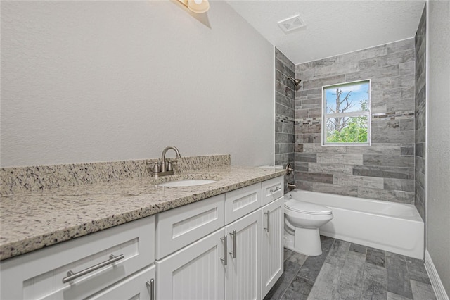 full bathroom with a textured ceiling, toilet, tile patterned flooring, tiled shower / bath, and vanity