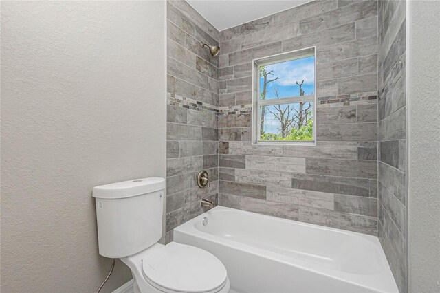 bathroom featuring tiled shower / bath combo and toilet