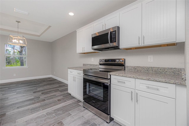 kitchen featuring white cabinetry, crown molding, light hardwood / wood-style floors, a tray ceiling, and stainless steel appliances